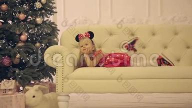 坐在圣诞树附近的白色沙发上的快乐小女孩